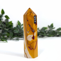 Yellow and white mookaite crystal tower with a label on a white background