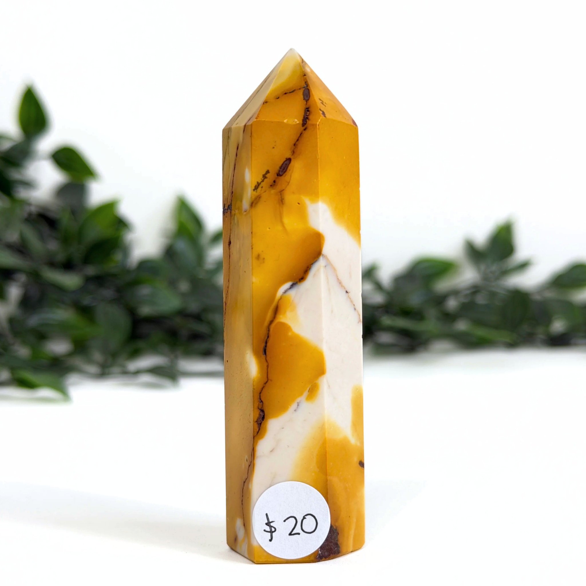Marbled yellow and white mookaite crystal tower with a price tag on a white background