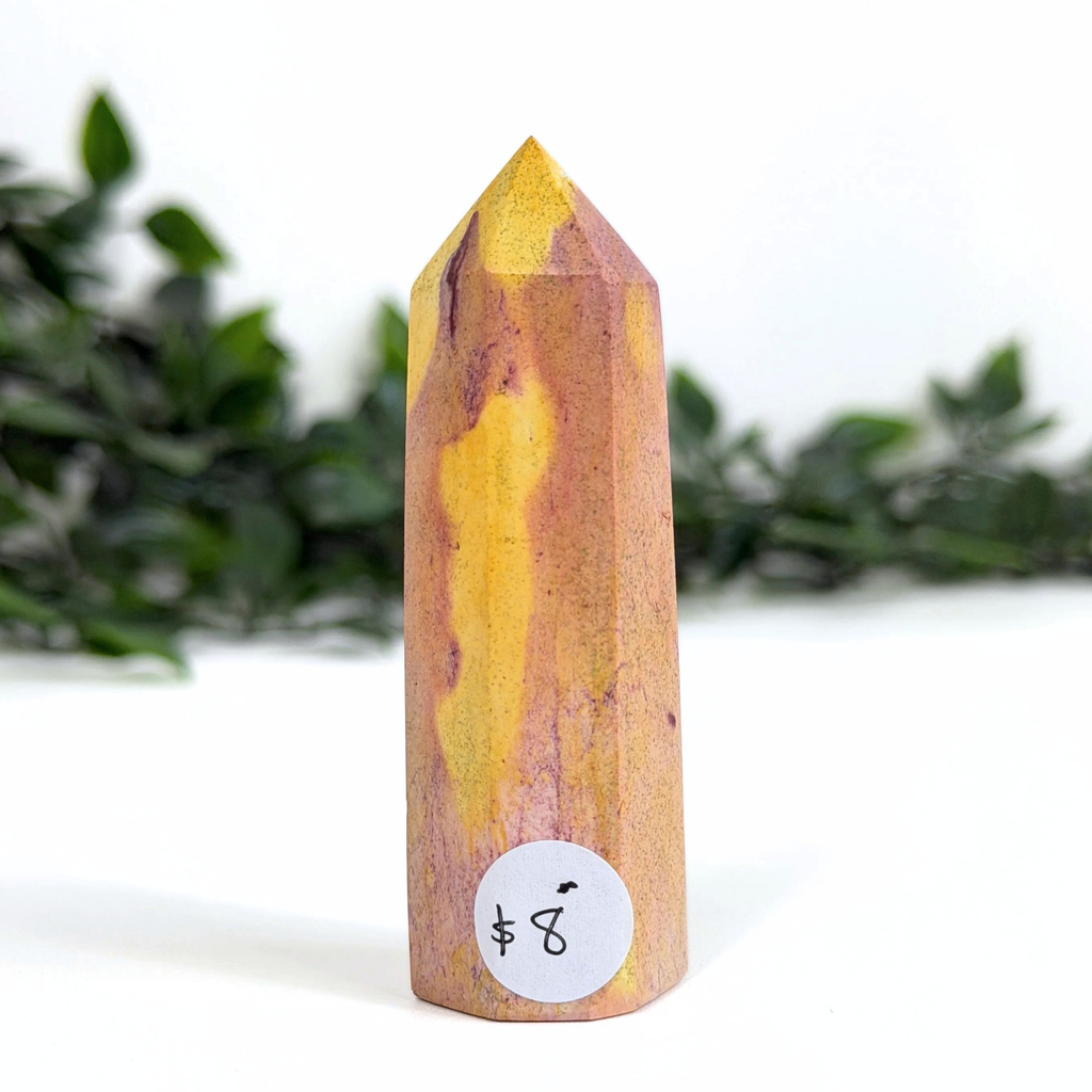 Colorful mookaite crystal tower with a label on a white background