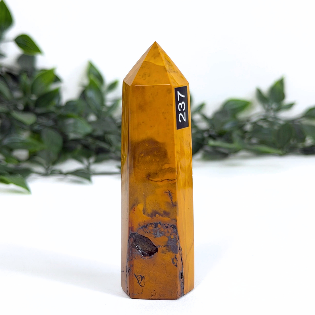 Yellow mookaite crystal tower with a black label on a white background