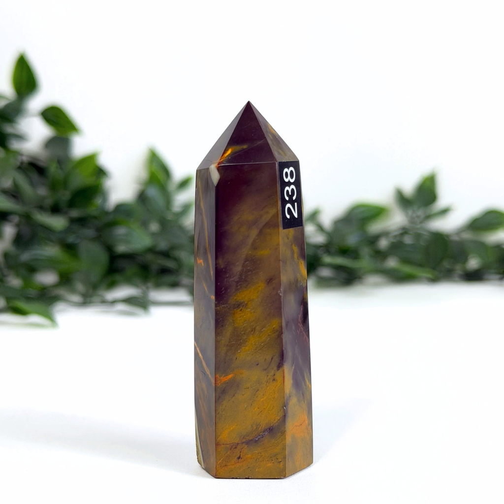 Dark mookaite crystal tower with number 238 on a white background with greenery