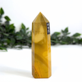 Yellow mookaite crystal tower with number 243 on a white background with greenery