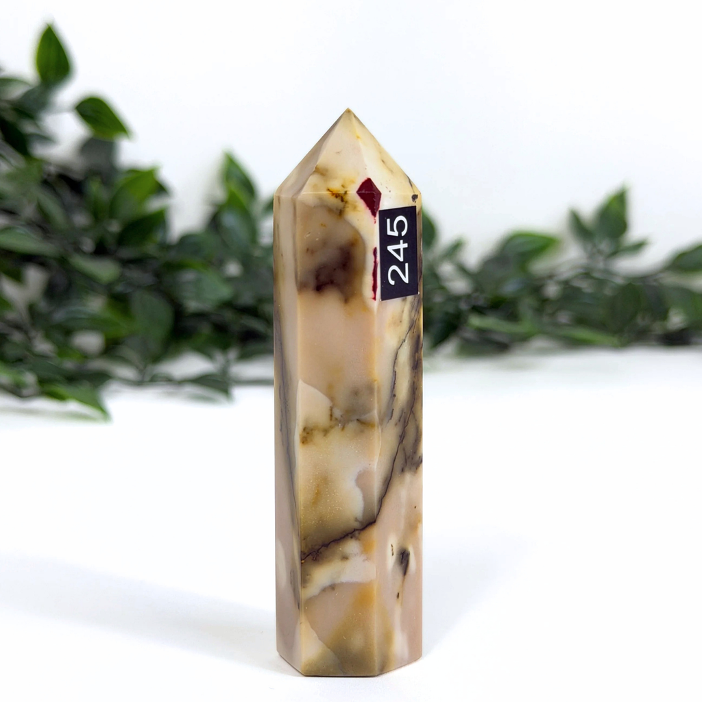 Marbled mookaite crystal tower with a label on a white background with greenery