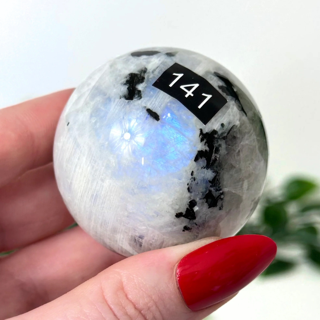 Moonstone crystal sphere held by hand on a white background
