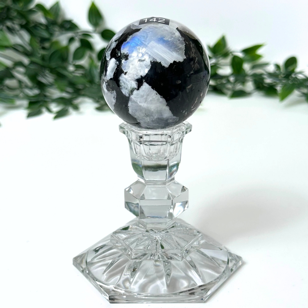 Moonstone sphere on a clear crystal base against a white background