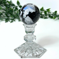 Moonstone sphere on a clear crystal base against a white background