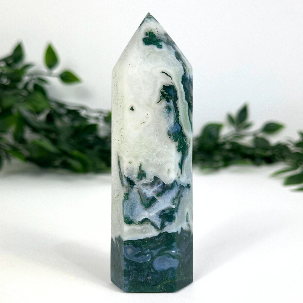 Moss agate crystal tower with green and white patterns on a white background
