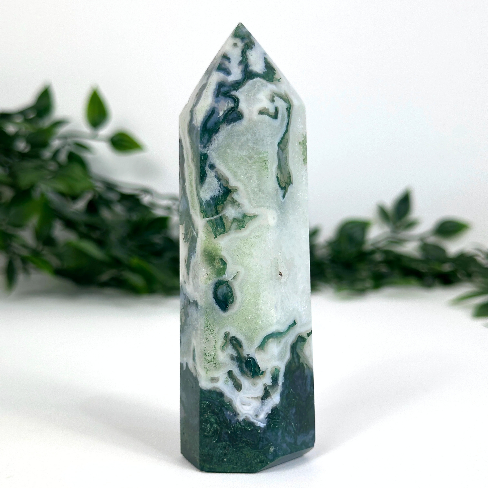 Moss agate crystal tower with green and white patterns on a white background