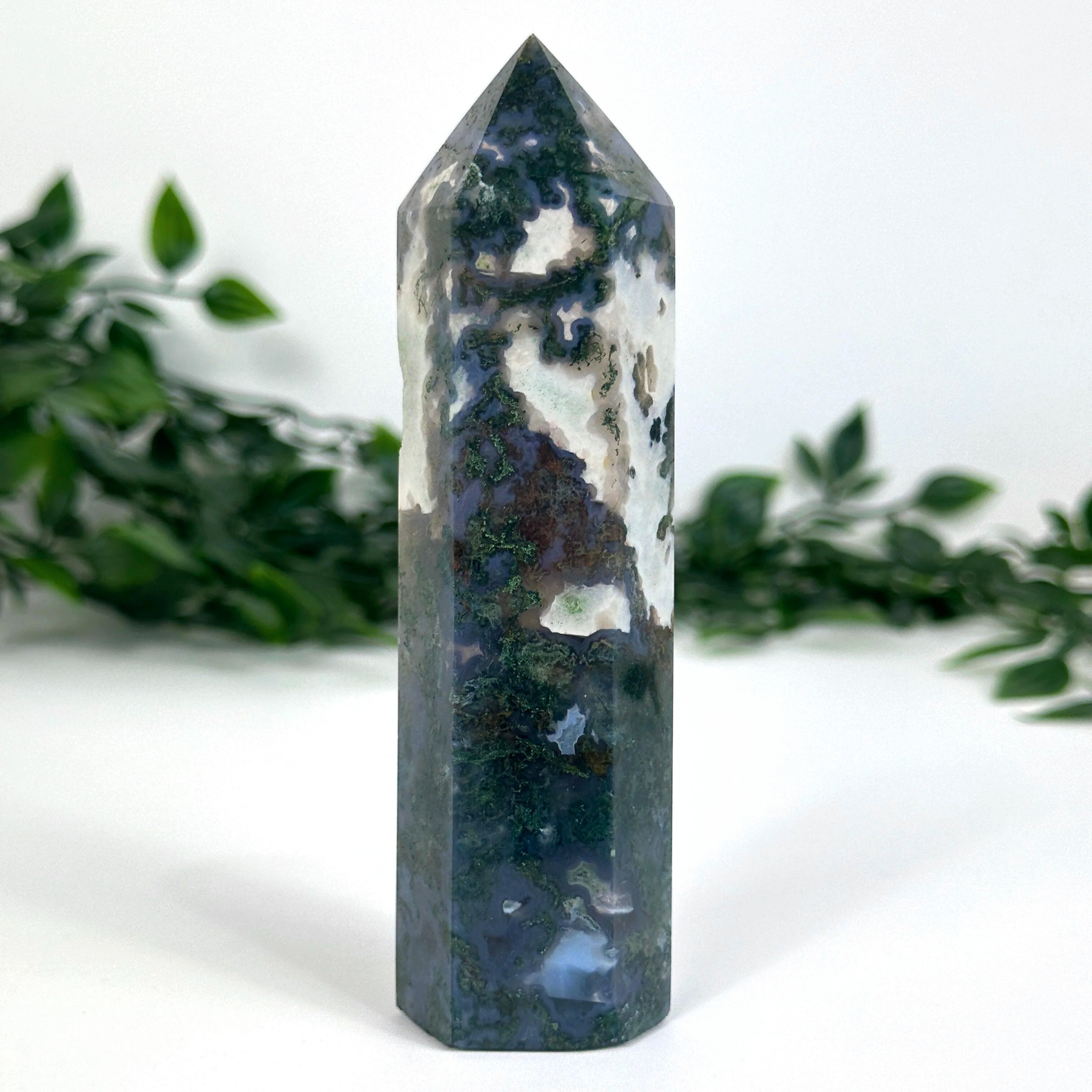 Moss agate crystal tower with natural patterns on a white background