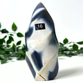 Orca agate free form with a number 16 label against a white background with green leaves.