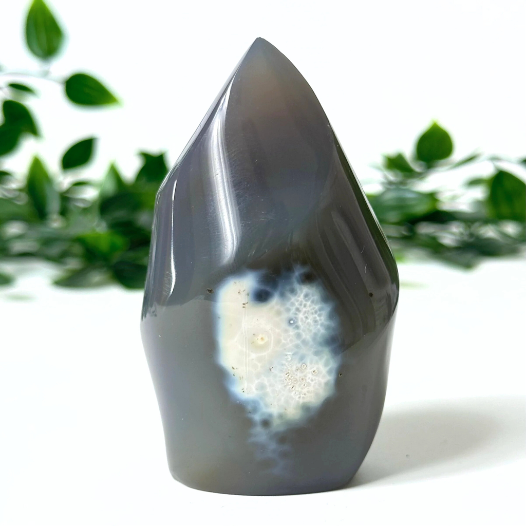 Orca agate flame set against a blurred natural background.