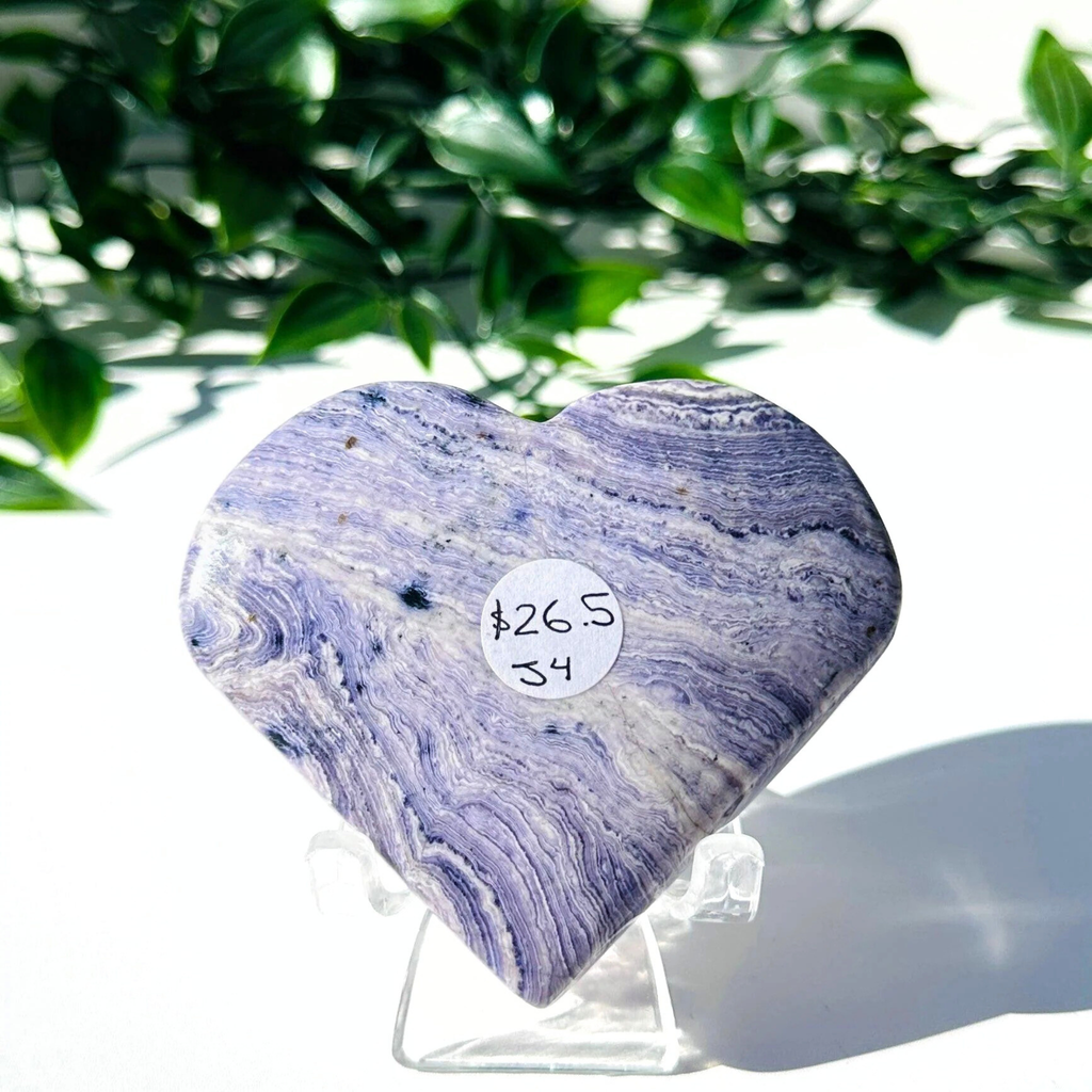 Purple fluorite and white chalcedony crystal heart on stand with a white leafy background