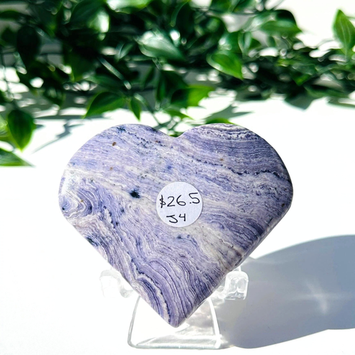 Purple fluorite and white chalcedony crystal heart on stand with a white leafy background