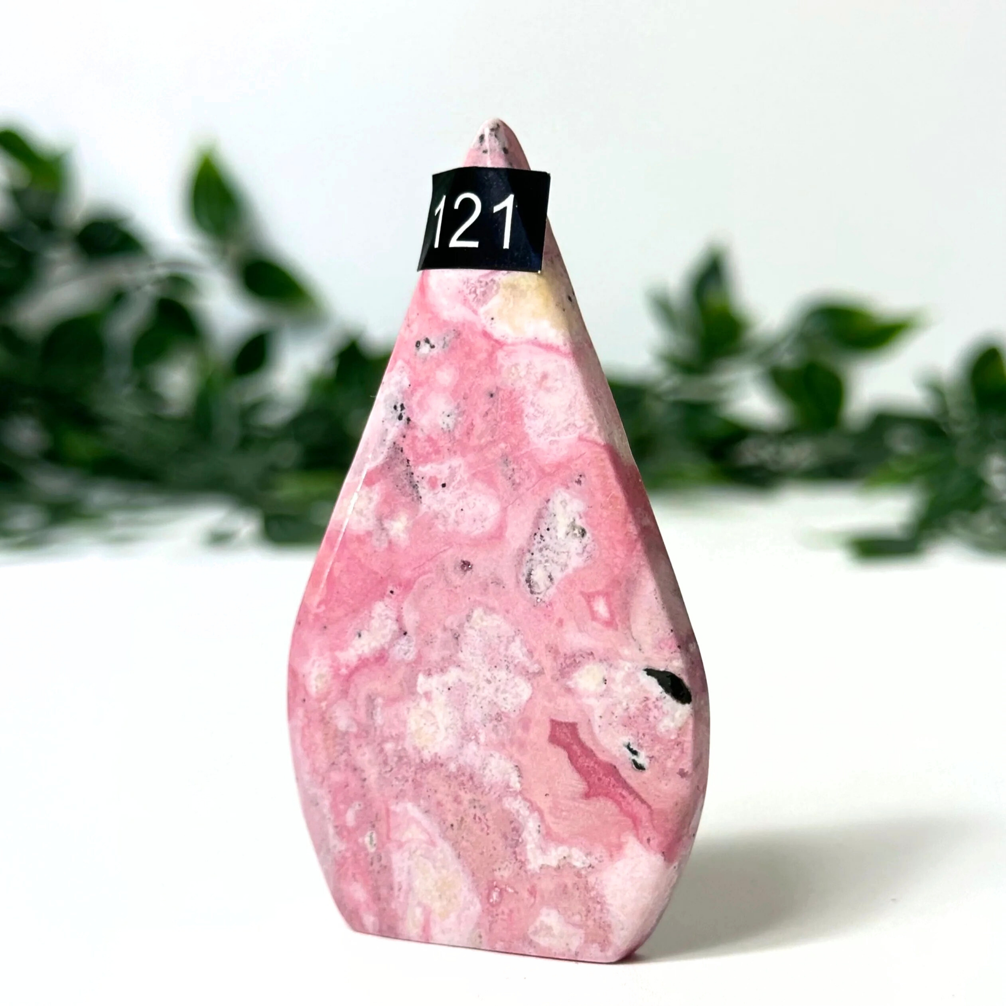 Pink marbled rhodonite crystal flame with a black label on a white background