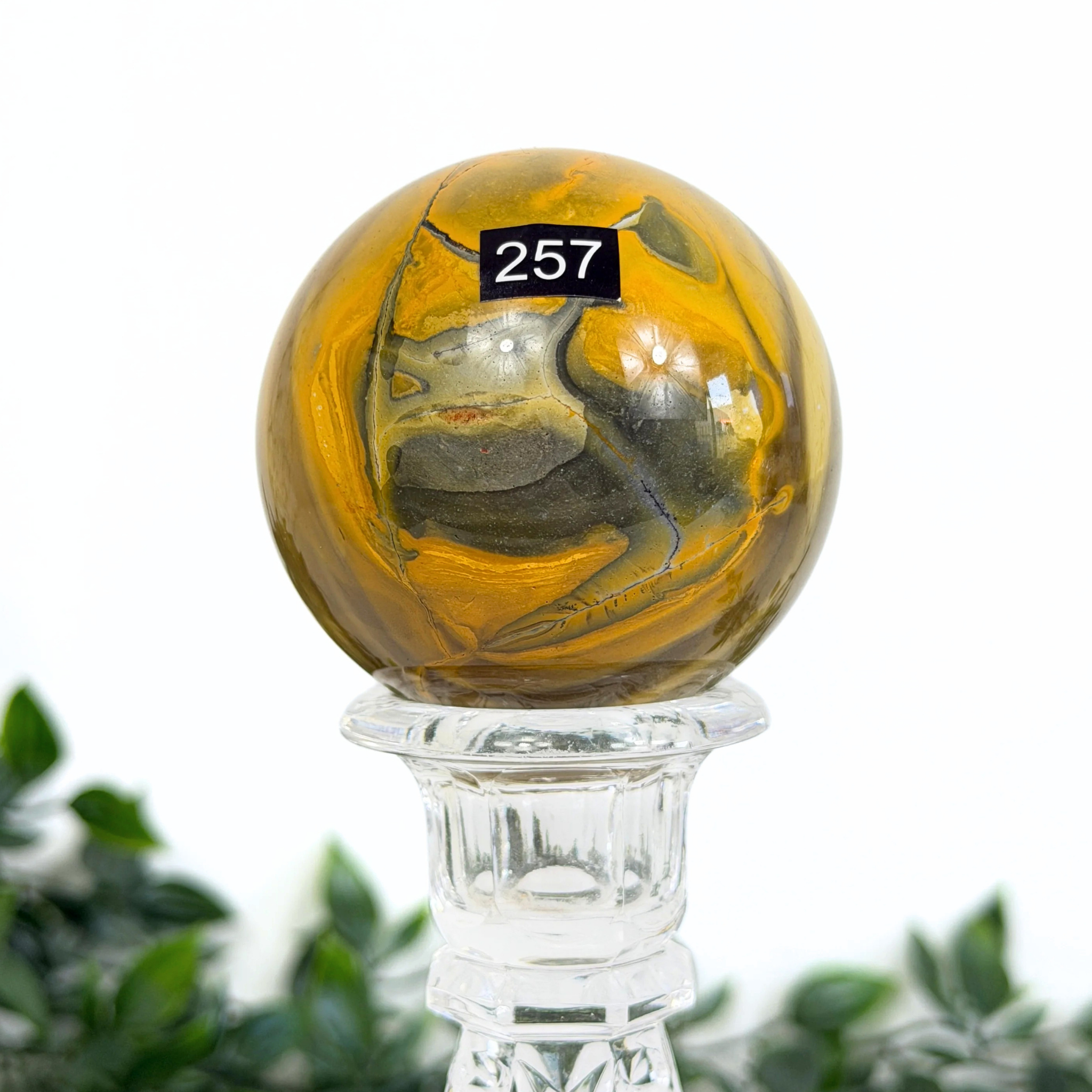 Mookaite crystal sphere with a glass stand on a white background