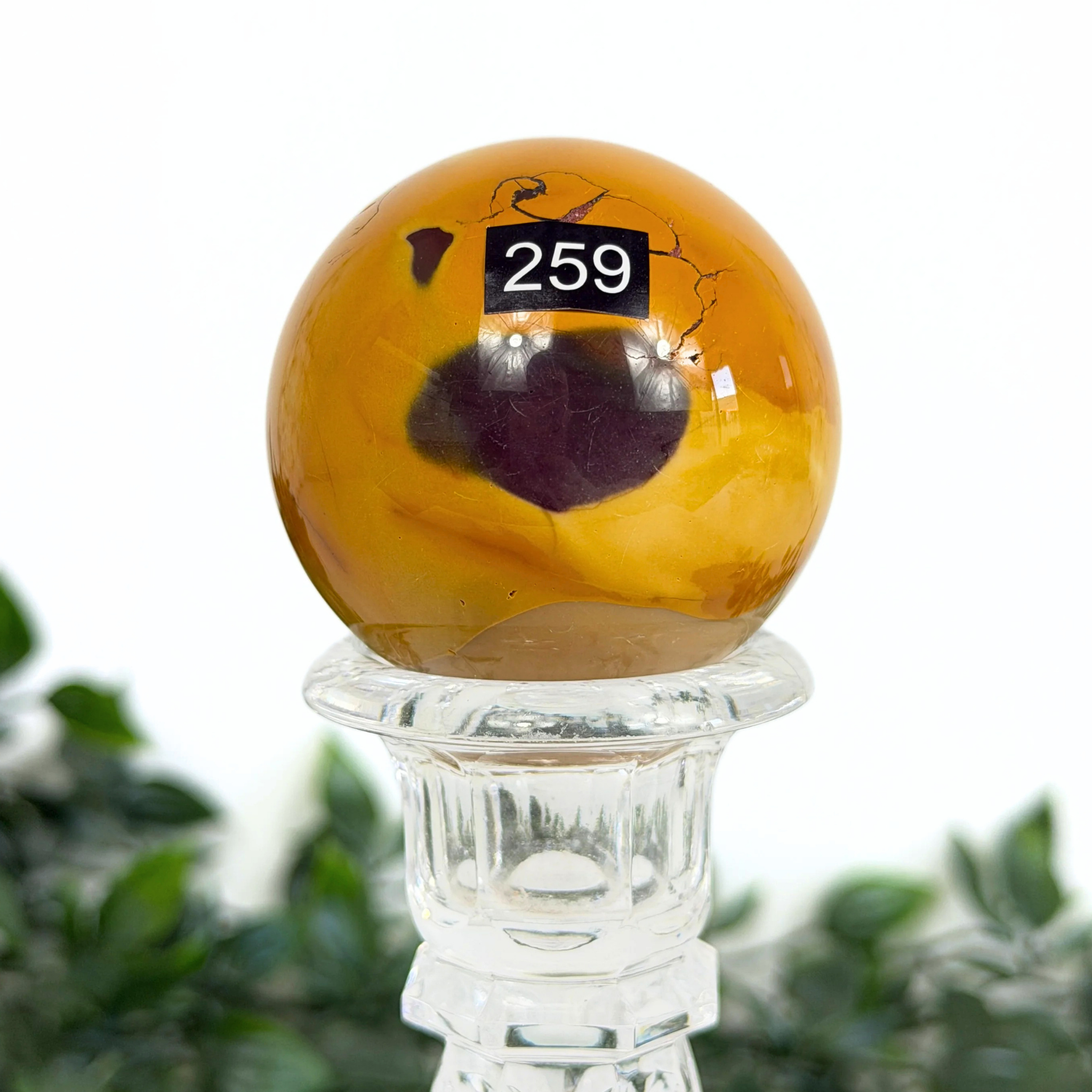 Decorative mookaite sphere with a stand on a white background