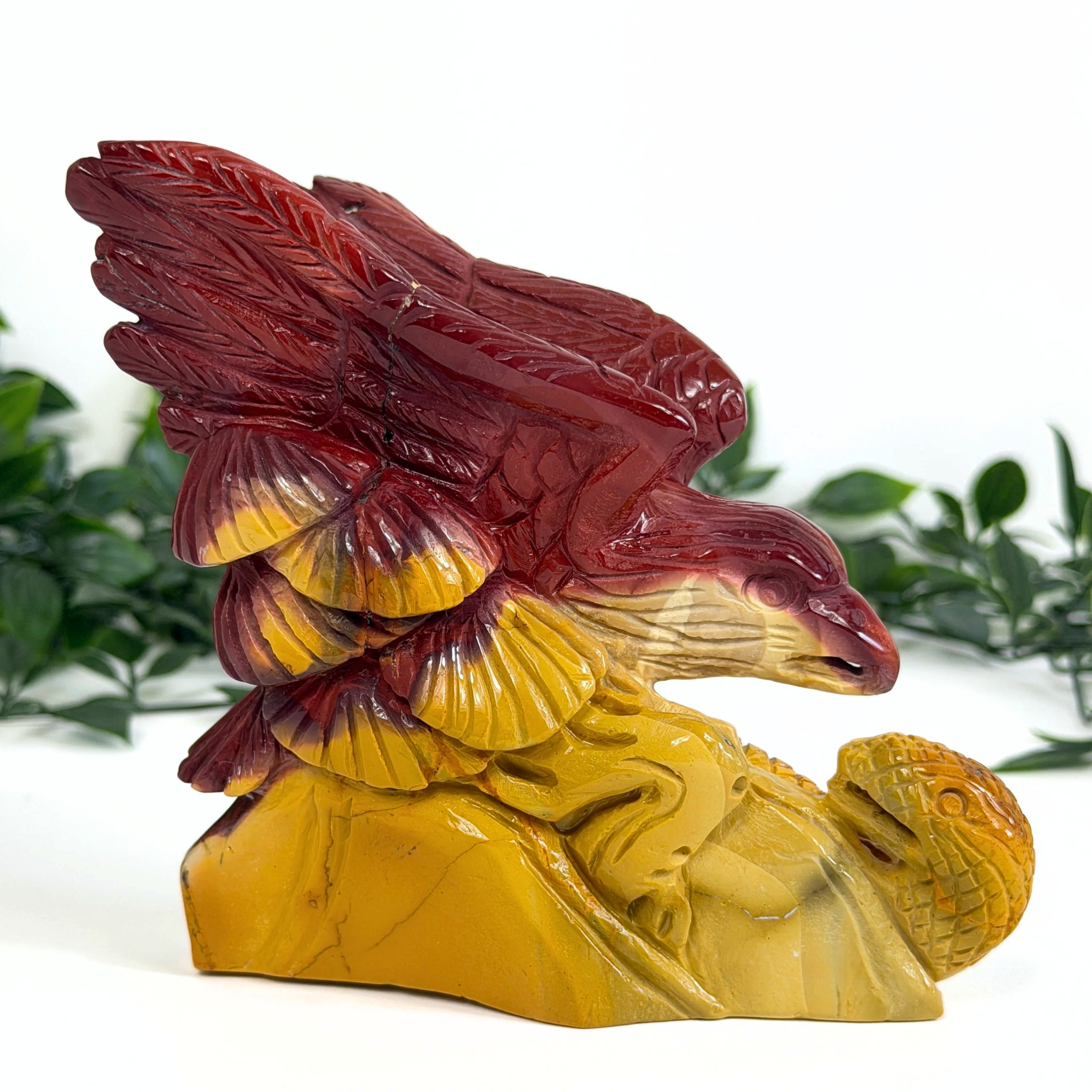 Mookaite crystal sculpture of an eagle with red and yellow colors on a white background