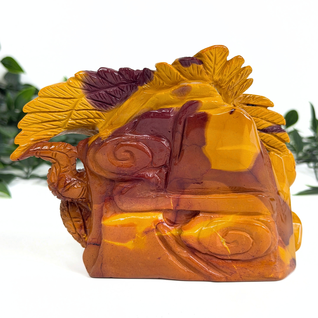 Carved mookaite piece with eagle and snake on a white background