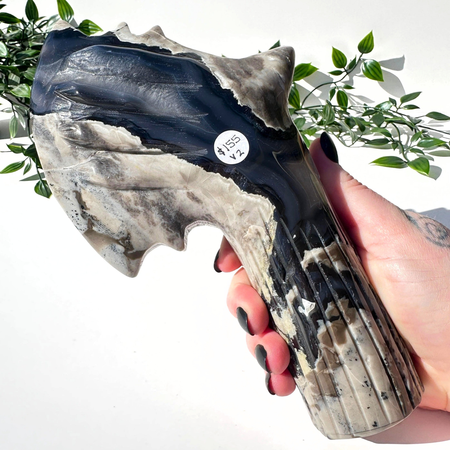 Hand holding a volcanic agate crystal axe against a white background
