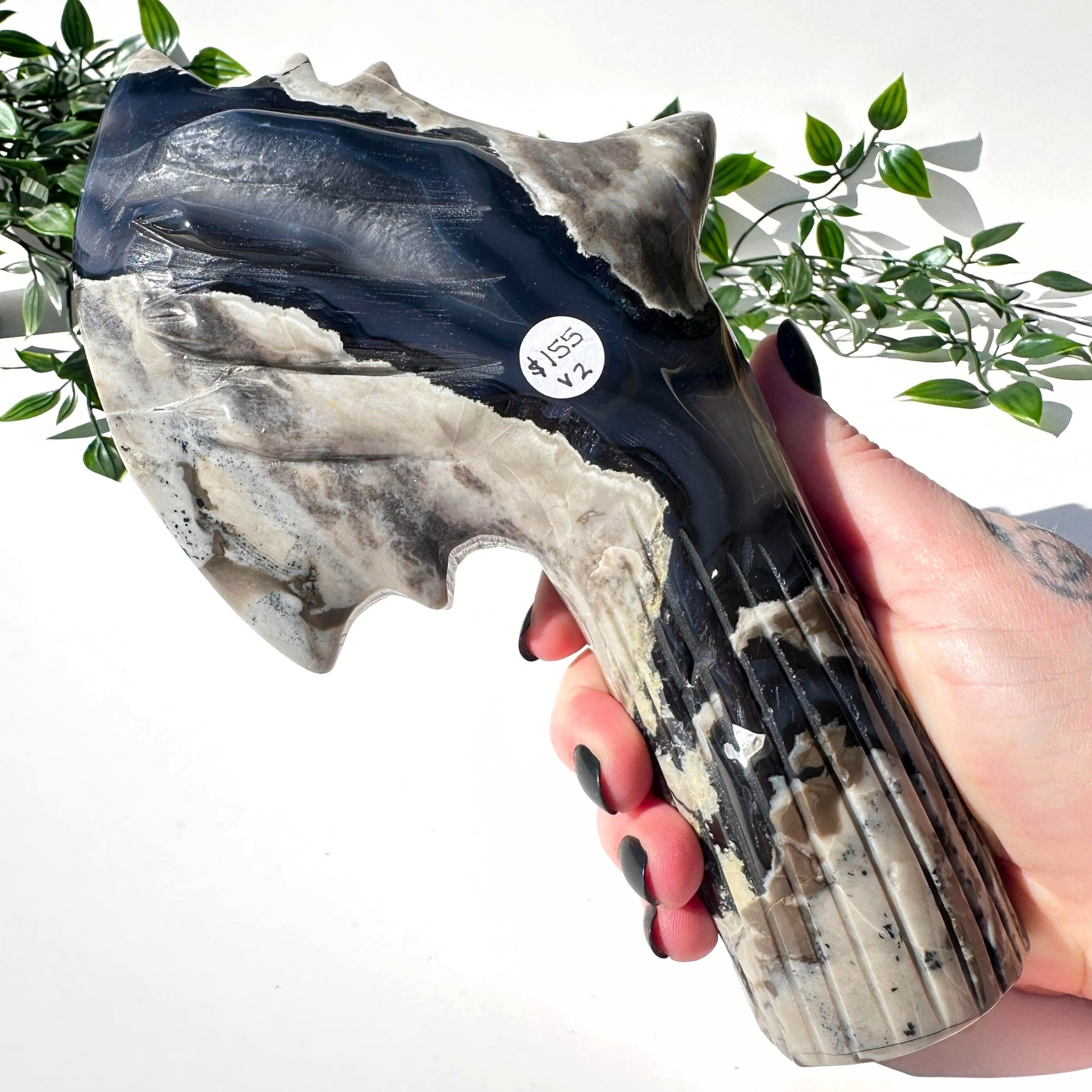 Hand holding a volcanic agate crystal axe against a white background